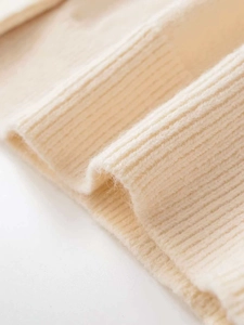 Close-up of off-white ribbed knit fabric with soft texture and rhinestone detail