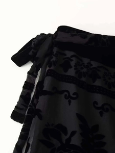 Detail aus schwarzem Ausbrenner-Stoff mit Samtblumenmuster und seitlicher Bindeschleife