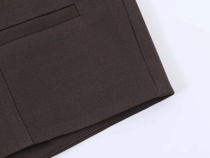Detail view of the fine stitching and dark brown fabric texture on a casual blazer pocket