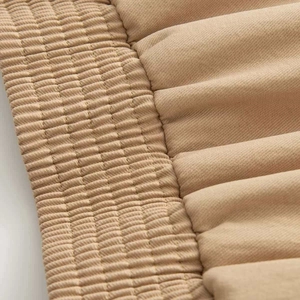Macro detail of khaki twill fabric showing exquisite quilted waistband and pleated texture