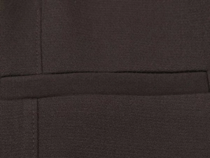 Close-up of the high-quality welt pocket detail and woven texture on brown blazer