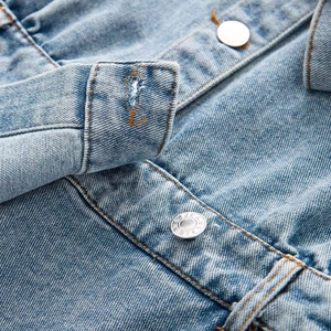 Close-up of denim dress cuff with metal button and high-quality stitching details