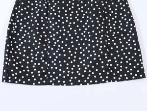 Vue détaillée de l'ourlet et du motif à pois blancs sur une robe noire fluide