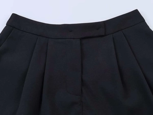 Detail view of high waist black trousers featuring professional pleated design and stitching