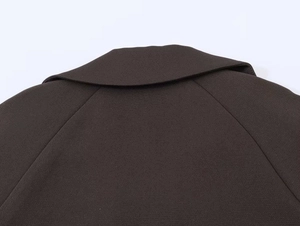 Close-up of raglan sleeve and notch lapel details on a dark brown blazer