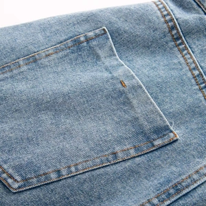Close-up of light blue denim dress showing back pockets with orange stitching detail