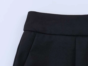 Detailed close-up of high-waisted black trousers featuring side pockets and smooth fabric