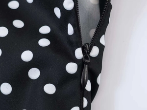 Gros plan détaillé d'une robe vintage à pois noirs avec fermeture éclair cachée et texture tissu