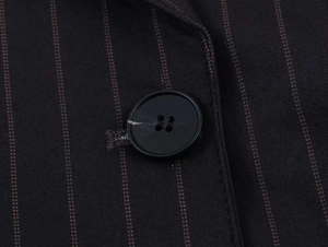 Close-up of pinstripe fabric detail with a black four-hole button and stitched buttonhole