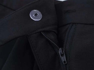 Detailed close-up of the black trousers showing a button closure and metal zipper detail