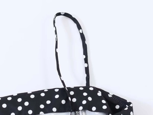 Détail d'un caraco noir à pois avec fines bretelles et finitions de couture soignées