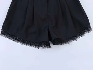 Detail view of black woven shorts featuring delicate eyelash lace trim on the bottom hem