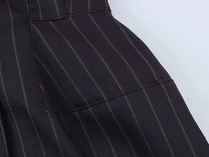 Detail of black vertical pinstripe dress showing flat side pocket and twill fabric texture