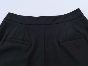 Detail of black woven suit pants featuring precision stitching and waist pleat design
