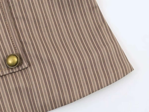 Close-up of brown striped blazer fabric with a vintage bronze metal button detail