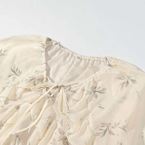 Detailed view of V-neckline floral chiffon top with ruffled edges and tie closure