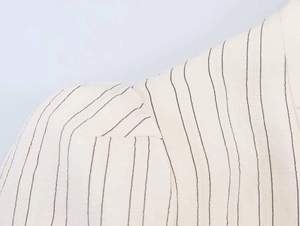 Close-up of pinstripe pattern and shoulder pleat detail on a beige cotton-linen blazer