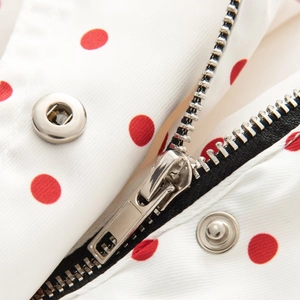 Detail of metal zipper and snaps on white jacket with red polka dot pattern