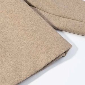 Close-up of beige thick wool fabric texture showing detailed woven fiber grain and soft finish