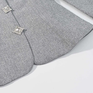 Close-up of grey tweed blazer featuring two elegant square rhinestone buttons for women