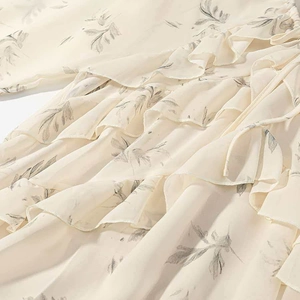 Close-up of light beige floral chiffon dress with ruffle details and waist tie