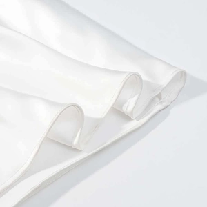 Detailed macro view of pure white silk dress hem featuring refined rolled edge stitching