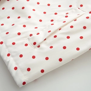 Close-up of white jacket with red polka dots showing pocket detail and fine stitching