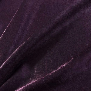 Detail shot of shimmering purple velvet fabric texture with elegant pleated drapery