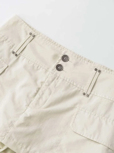 Détail d'une jupe cargo à taille haute avec fermeture à double bouton et rivets