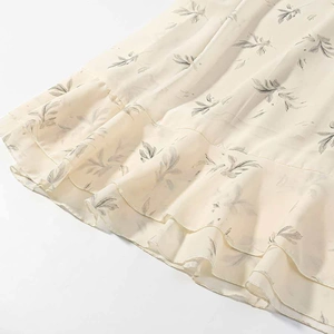 Detailed macro view of the ruffled hem and floral print on the beige summer dress