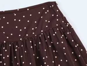 Close-up of high-waisted brown polka dot pants with side hidden zipper and pleat detail