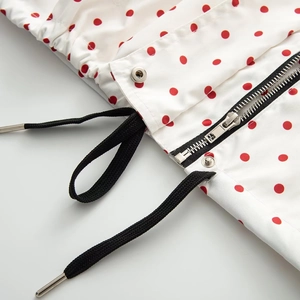 Detail view of high-quality silver zipper and black drawstrings on red polka dot jacket