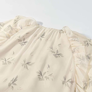 Close-up of floral chiffon top with ruffled shoulders and pleated neckline details