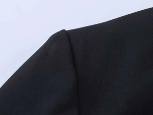 Close-up detail of high-quality black suit fabric showing shoulder seams and texture