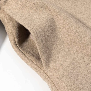 Close-up of side pocket detail on a khaki wool coat with high-density fabric texture