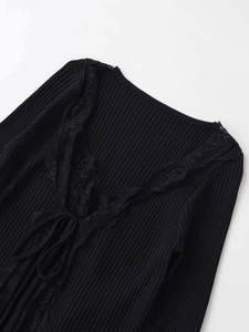 Detail of V-neck ribbed knit top featuring delicate lace trim and ribbon tie closure