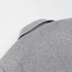 Macro detail of the gray blazer collar showing refined twill fabric and premium stitching