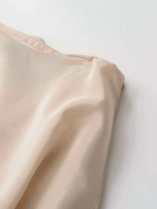 Detailed macro view of the champagne satin fabric texture and premium stitching on the skirt