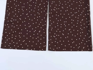 Detailed close-up of dark brown polka dot fabric and texture on wide-leg trousers