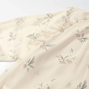 Detailed view of light yellow chiffon fabric with delicate floral prints and ruffled edges