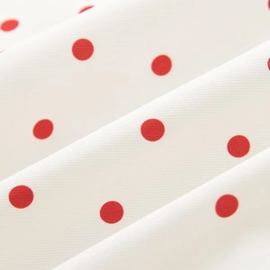 Detail of red polka dot pattern on white fabric with soft draped texture and weaving