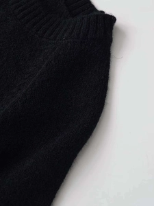 Dettaglio macro del maglione in maglia nera con perle finte e strass applicati