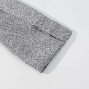 Detailed close-up of grey textured fabric on a tailored blazer with precise stitching