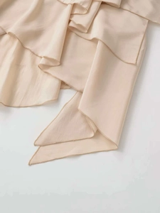 Close-up of beige tiered ruffles showing silky fabric texture and draping on the skirt