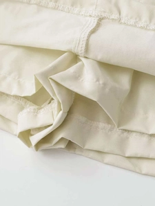 Détails des coutures d'une jupe trapèze beige et texture du tissu léger de qualité