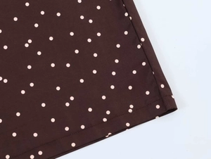 Detailed close-up of brown polka dot fabric showing precision stitching and fine texture