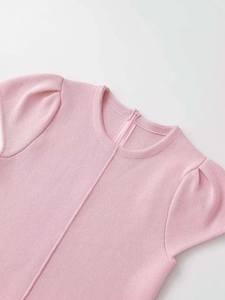 Detail of pink knit top featuring delicate puff sleeves and seamless crew neckline design