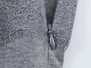 Makro-Detail von Spitzenbesatz und grauem Strickstoff mit verdecktem Reißverschluss