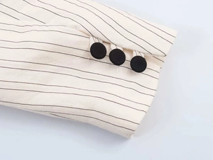 Detailed close-up of striped blazer cuff featuring three classic black buttons
