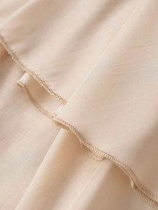 Detail shot of apricot ruffled skirt featuring layered chiffon fabric and fine hem stitching